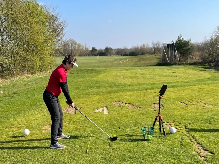 Female golfer training with launch monitor on driving range.