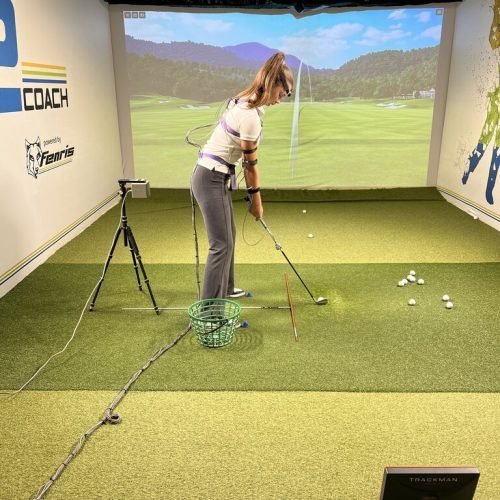 Female golfer practicing indoors with 3D motion analysis sensors and TrackMan golf simulator