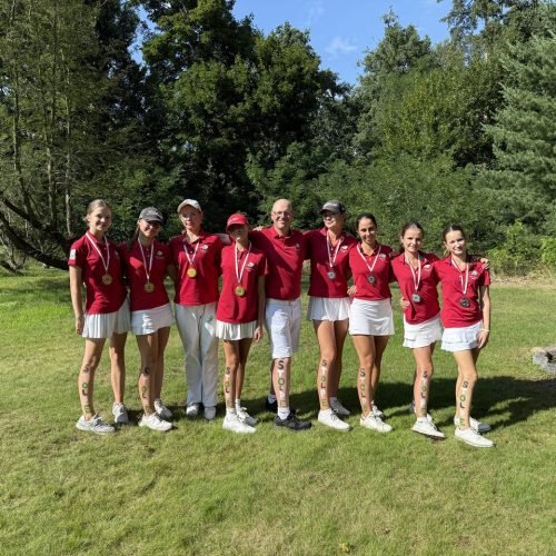 Golf team Stolper Heide with coach celebrating tournament win, players in red shirts and medals on the golf course
